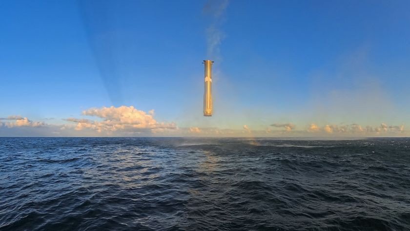 A giant metal cylinder hovers above a sea in front of a blue sky.