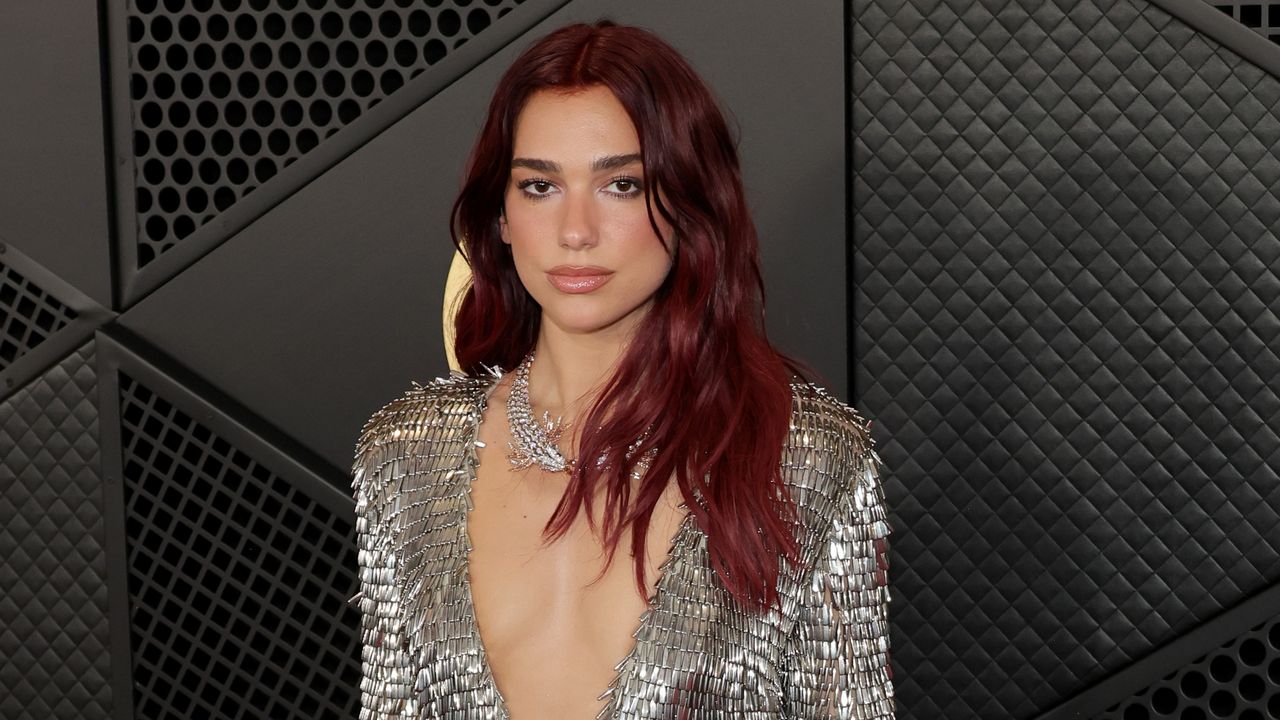 Dua Lipa is smiling to the camera at the Grammy&#039;s red carpet.