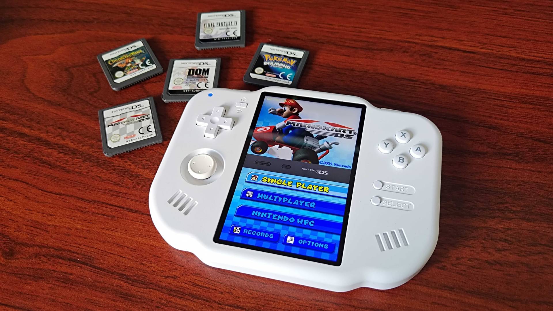 MagicX Zero 40 on a woodgrain desk with Mario Kart DS menu on screen and DS cartridges on top left.