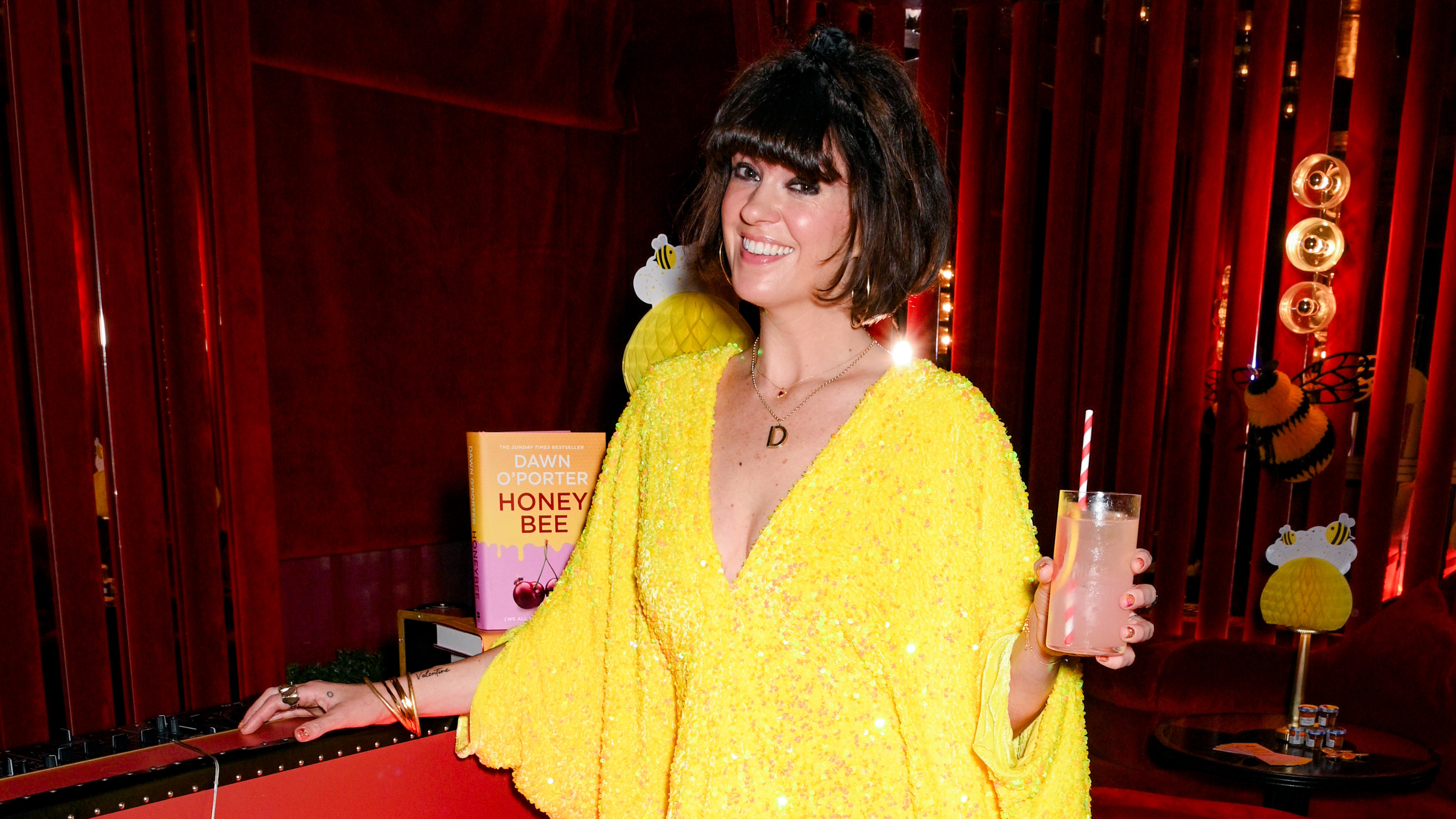Dawn O'Porter in bright yellow sequined gown holding a drink.
