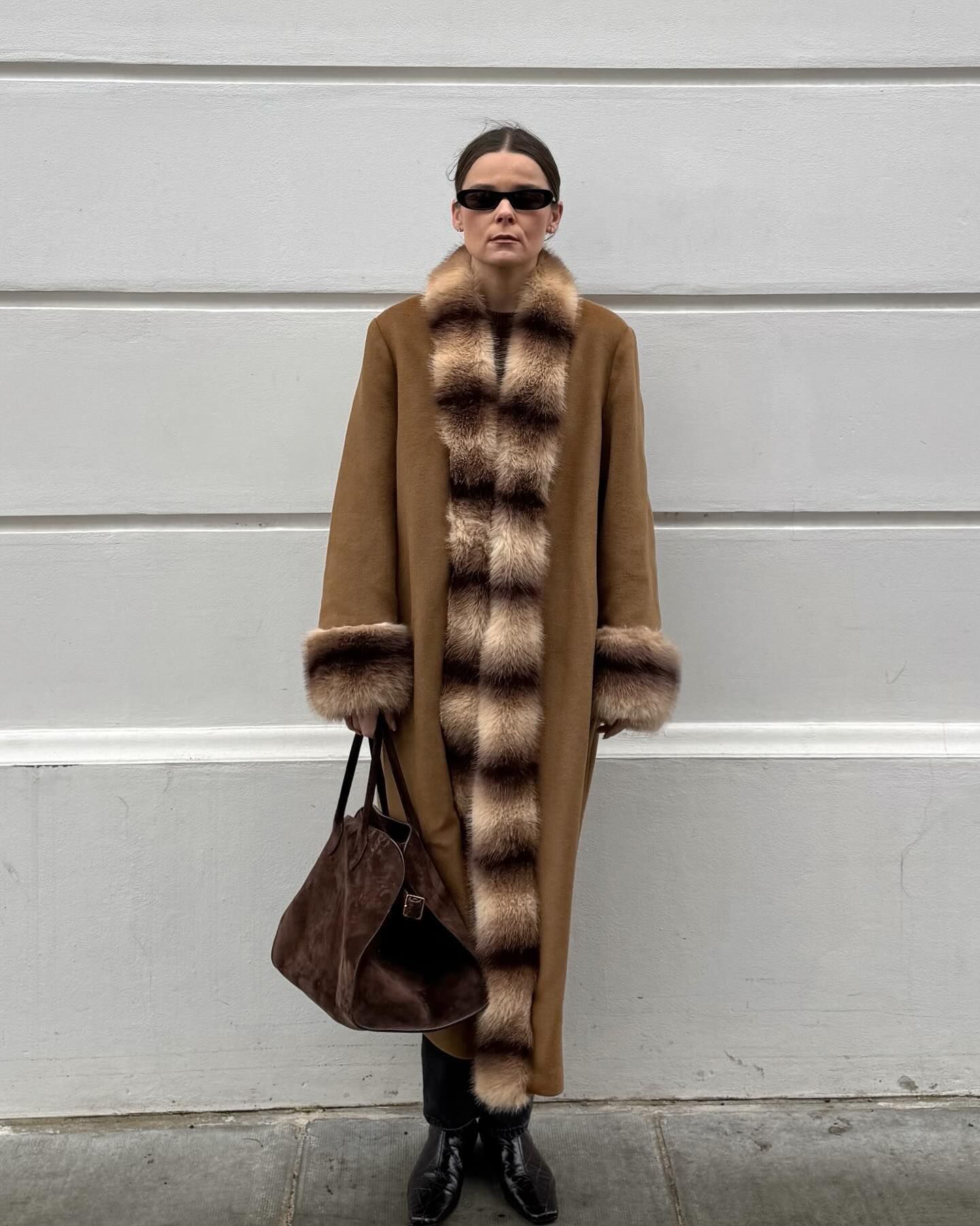 Rikke Krefting wearing a brown, fur-trim coat with black pants, black boots, and a brown suede The Row Margaux bag.