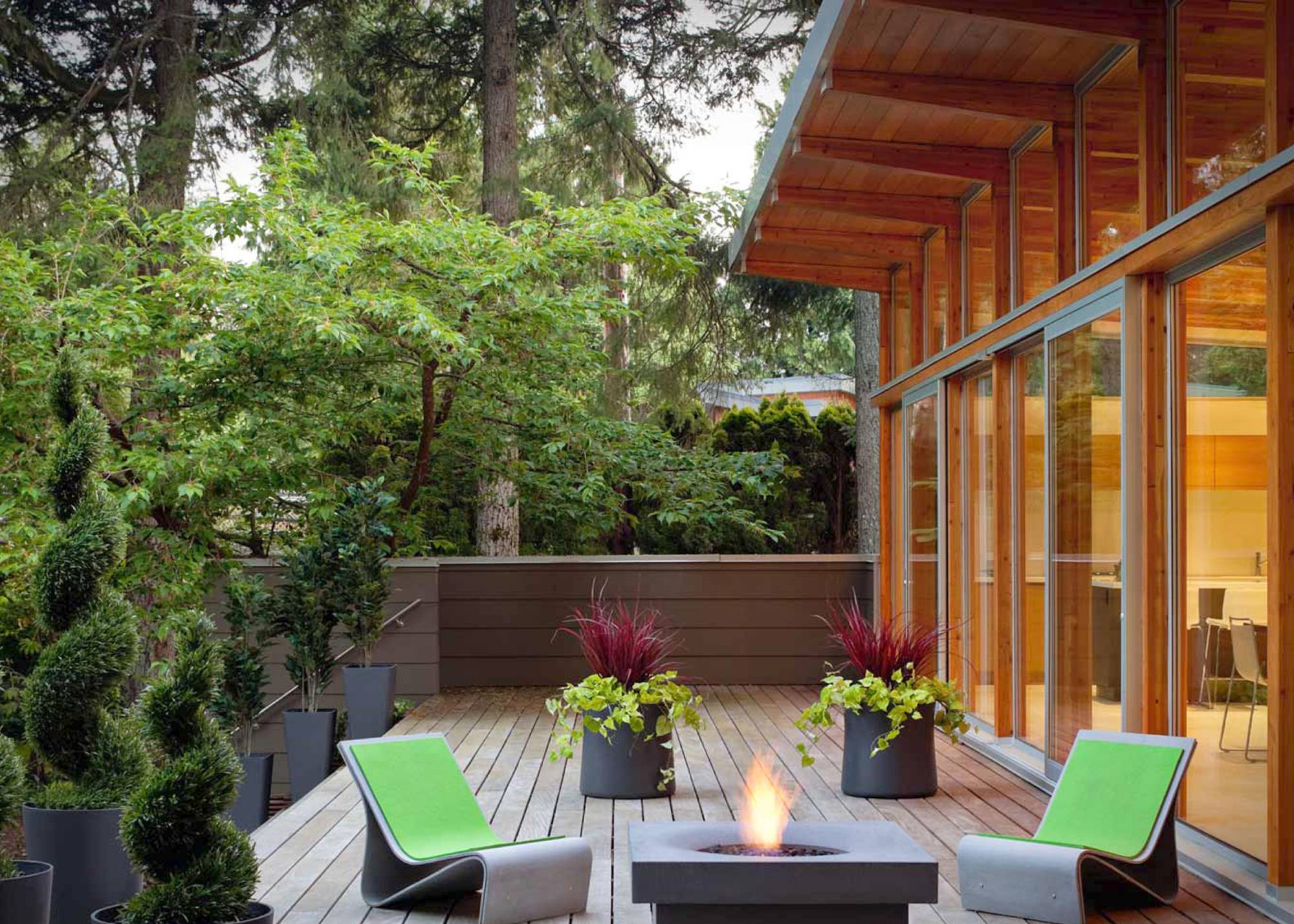Decking outside modern home with green seating and trees