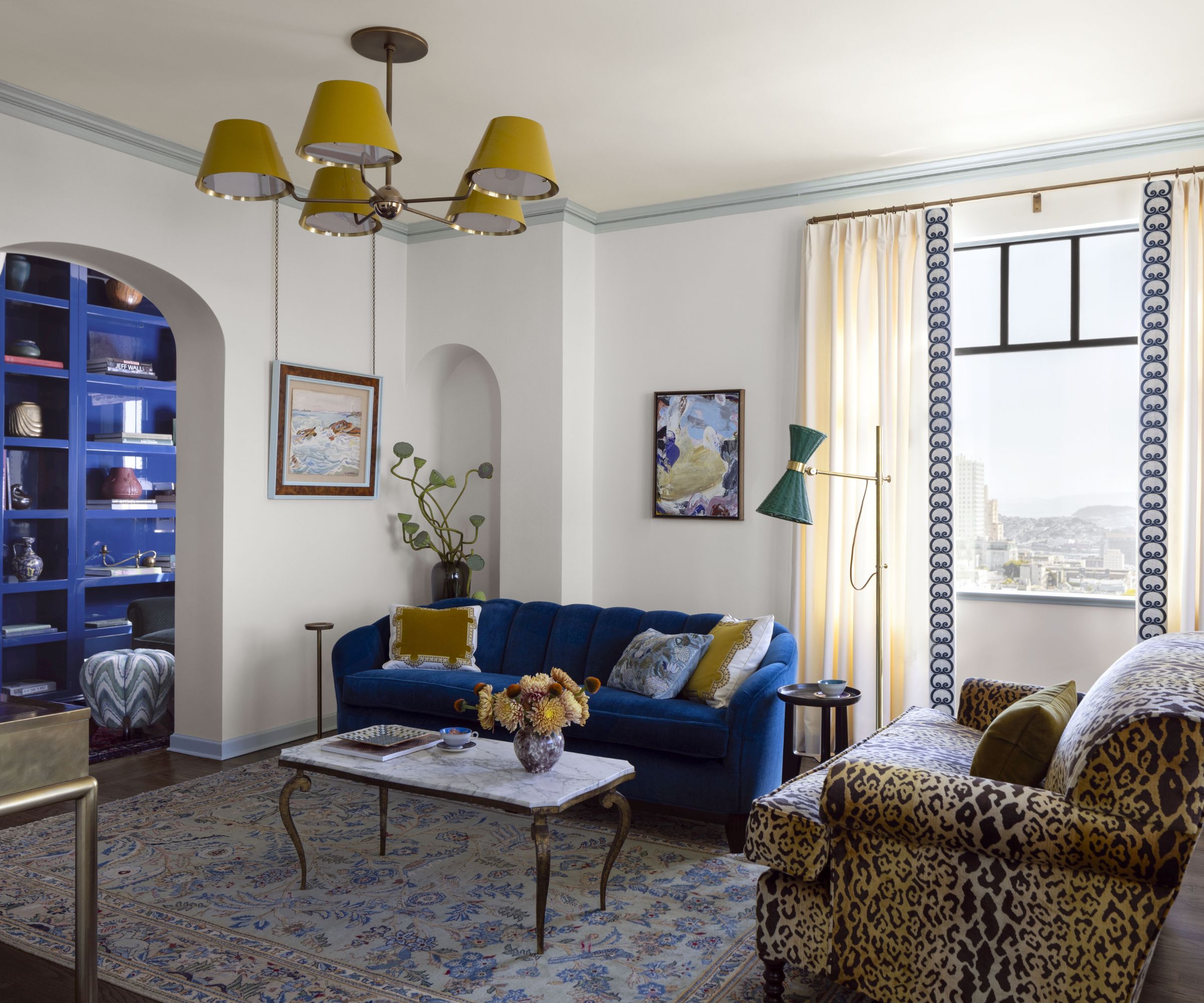 White living room with blue sofa and leopard print armchair with yellow throw pillows