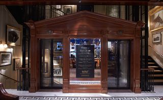 Two elevators with a mirror with signage on it between them and a staircase on either side of them.