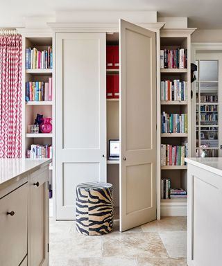 Bookshelves and bespoke cabinet doors hiding small workspace, stool covered in Zebra print fabric.