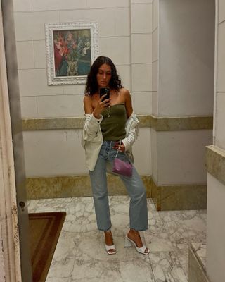 Italian influencer Giulia Tordini wearing a tube top, white denim jacket, blue straight-leg jeans, and Attico white block-heel mules