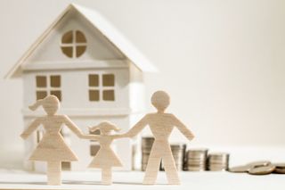 Cutout family in front of house and coins