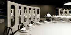 A black-and-white dining room is furnished with spectacular sculptural pieces including a multi-mirror room divider in white sleek plaster, huge round tables with black bistro table chairs, industrial-style pendant lighting, wine glasses, and silver serveware.