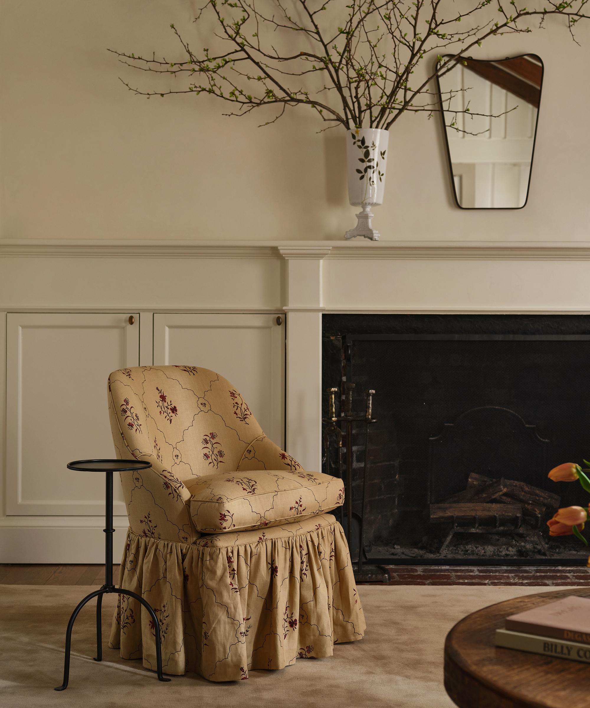 fireplace with a frilly chair in front of it and a mirror above it