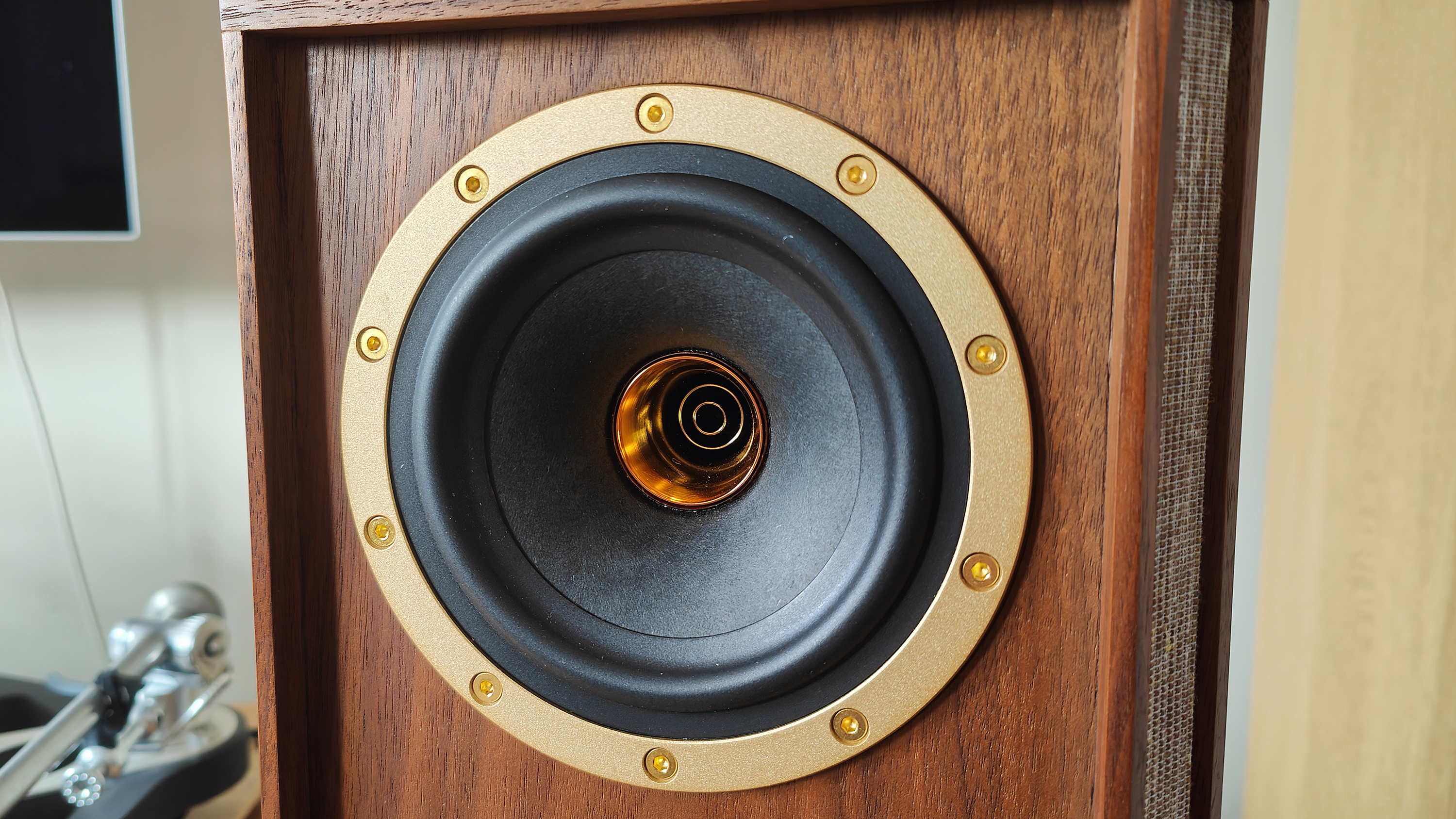 The Tannoy Autograph Mini pictured in a room next to a wooden sideboard and a record player