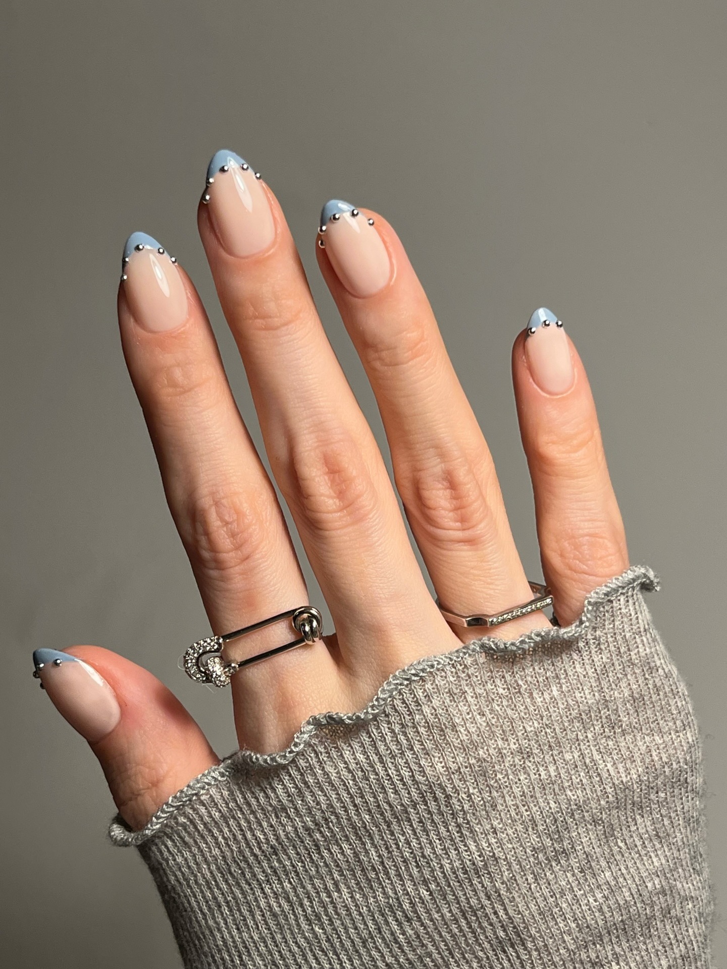 A blue French tip manicure with silver studs