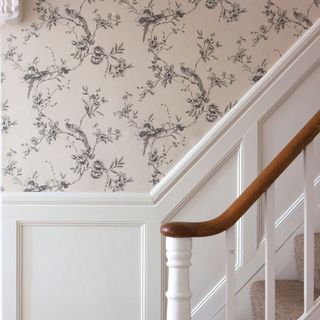 Monochrome toile wallpaper going up the stairs with a white panel