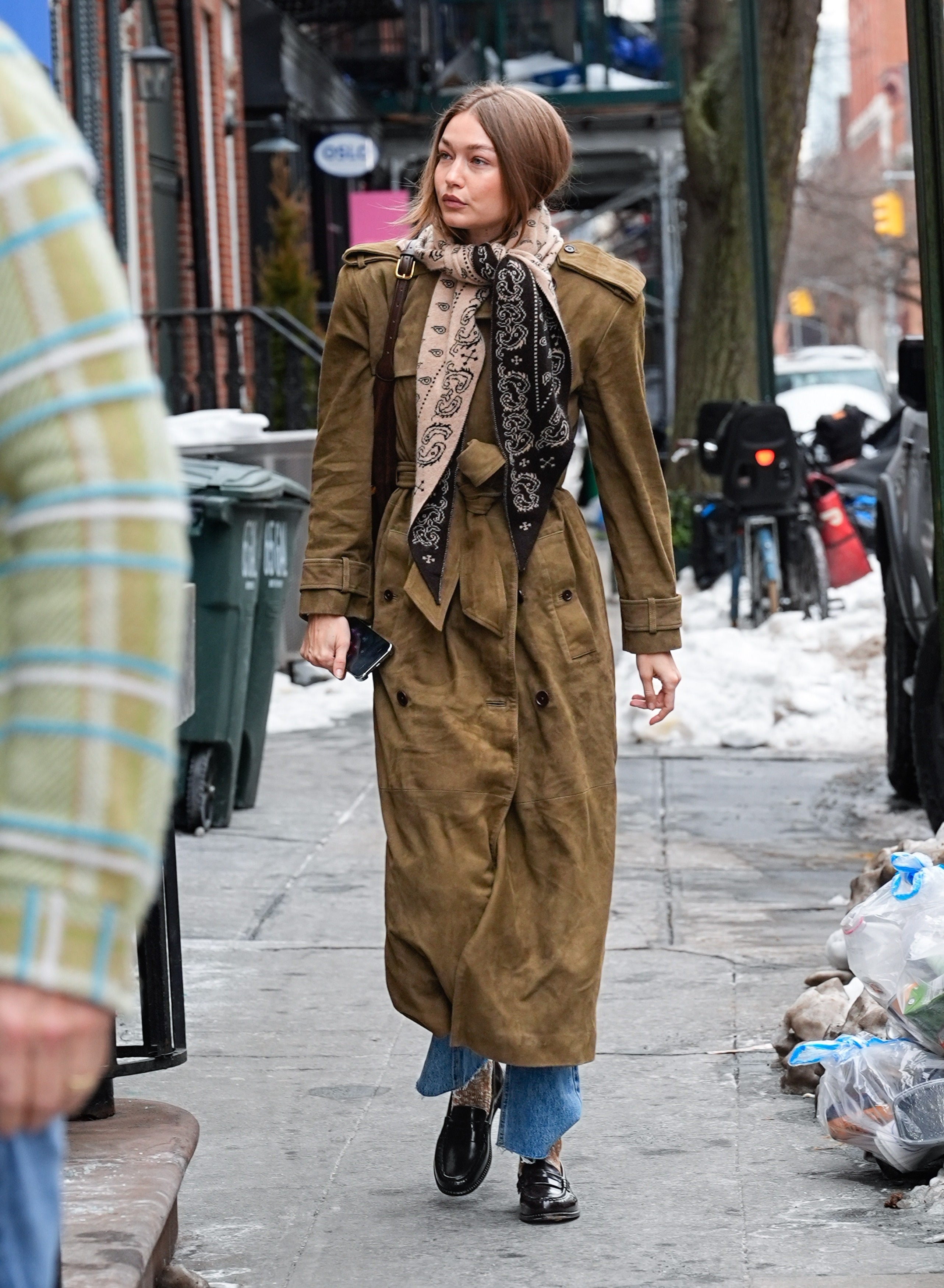 gigi hadid wearing a suede coat, jeans, loafers, and a bandana