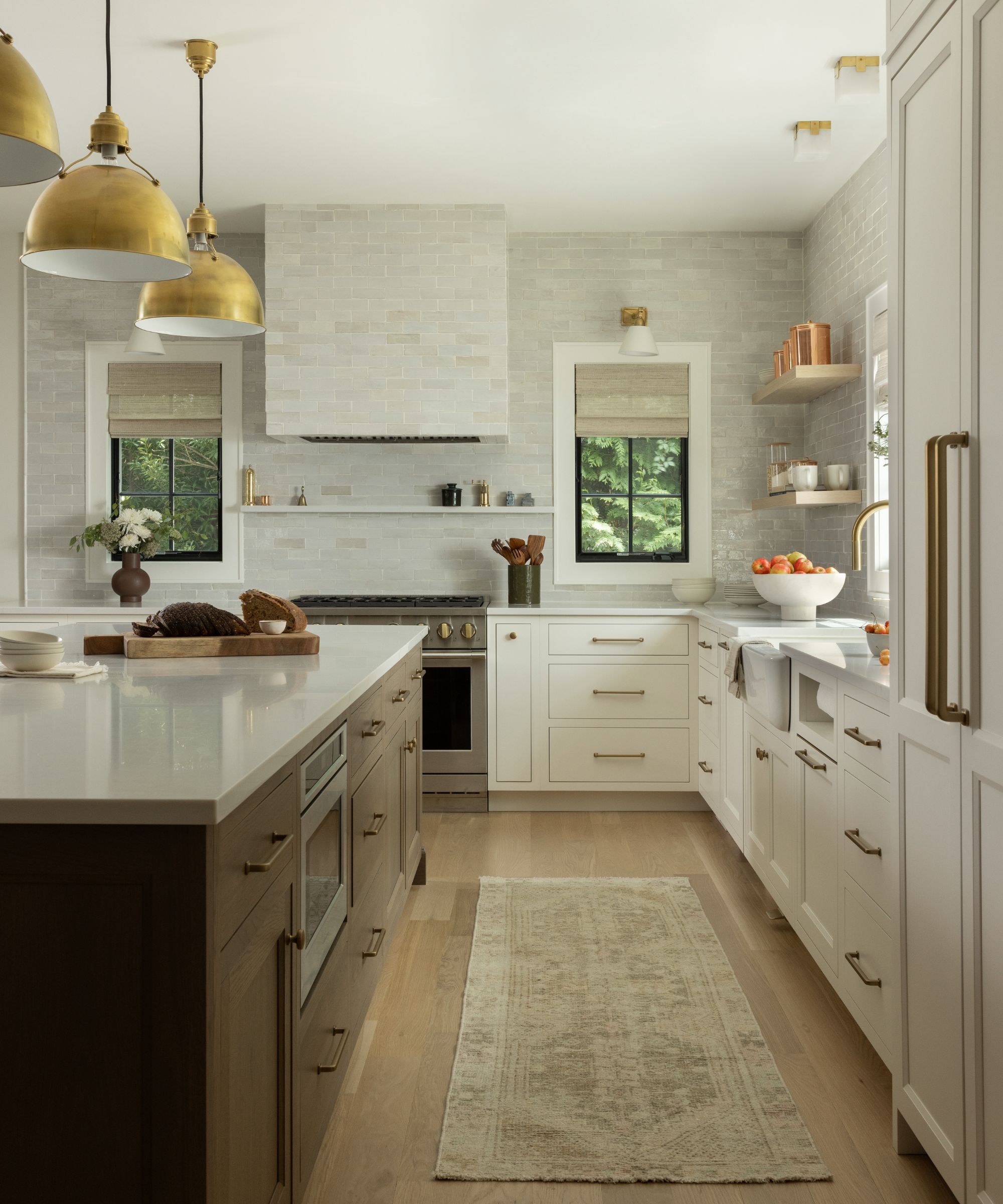 A neutral kitchen with white cabinets, a wooden island, and backsplash tiles that go all the way to the ceiling