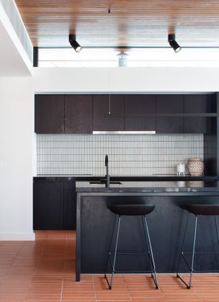 A kitchen with wooden flooring and ceiling and black painted cabinets