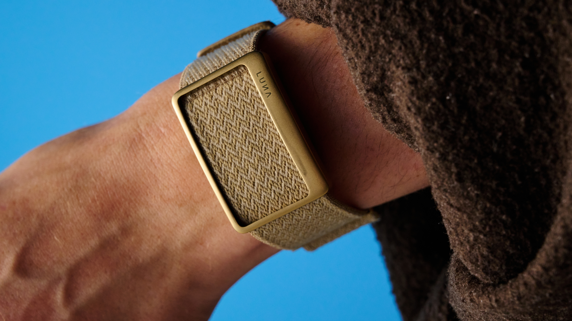 the luna band in beige photographed with the blue tom's guide background being worn by the author