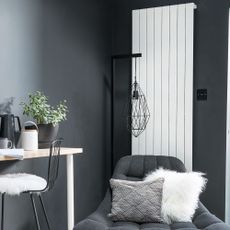 Grey living room with white vertical radiator behind grey armchair