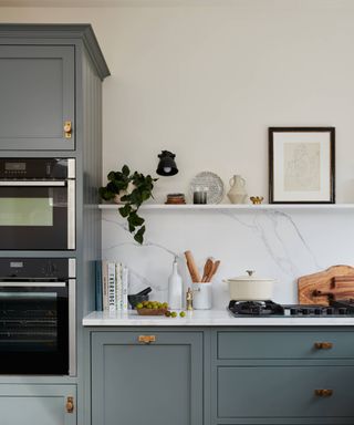 blue kitchen with brass handles and marble splashback