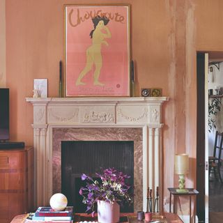 A living room with peach-coloured walls and fireplace bearing an artwork