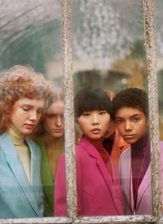 four women in colorful turtlenecks and blazers