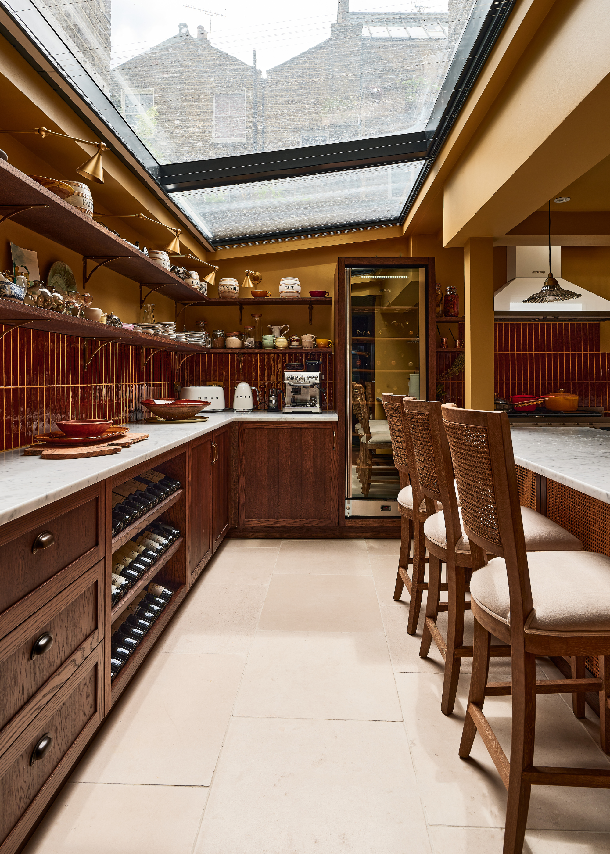 a dark brown, wooden kitchen with cola tiles and mustard walls. A large skylight fills the kitchen with light