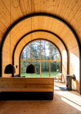 Wooden barrel ceiling over a living space that looks out onto a garden