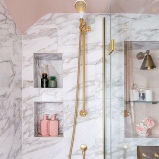 marble effect tiles around gold shower with niche shelving