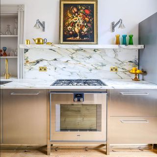 metallic kitchen with marble countertop and splashback and mirrored kickbacks and silver oven