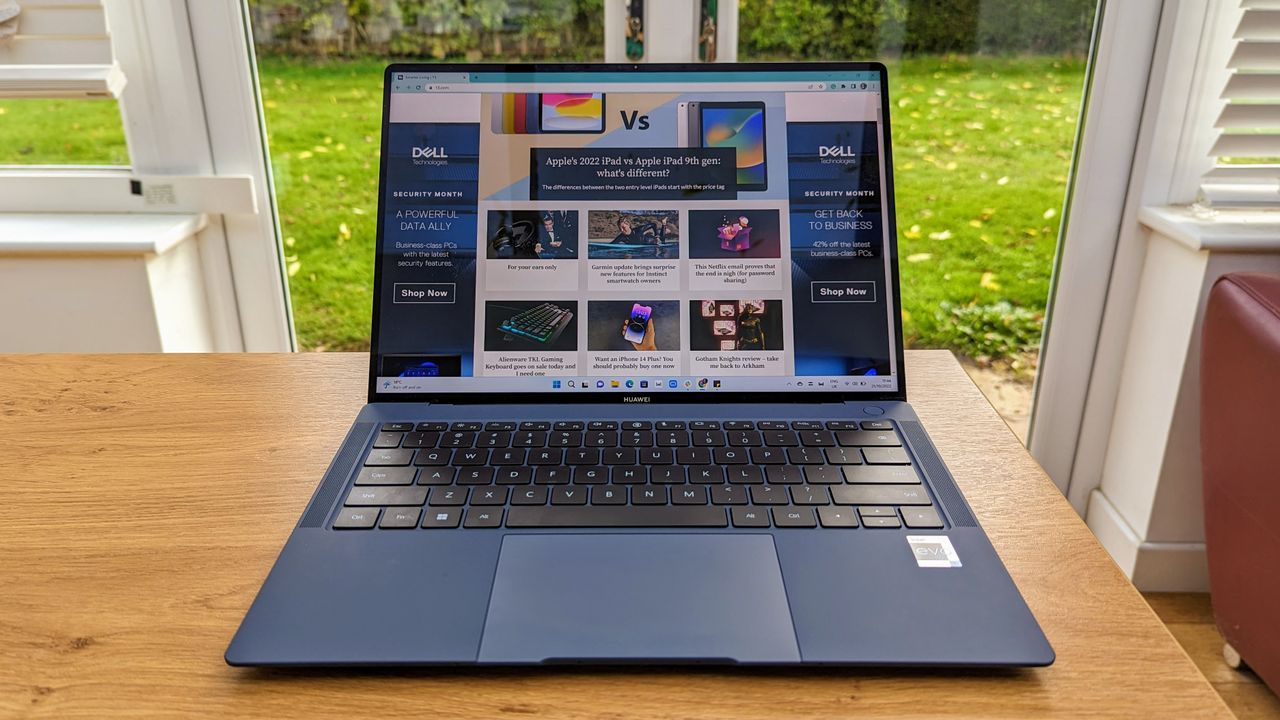 Huawei Matebook X Pro (2022) review: laptop open on wooden table by large windows