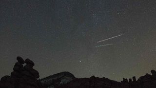 Several meteors can be seen streaking across a starry night sky.