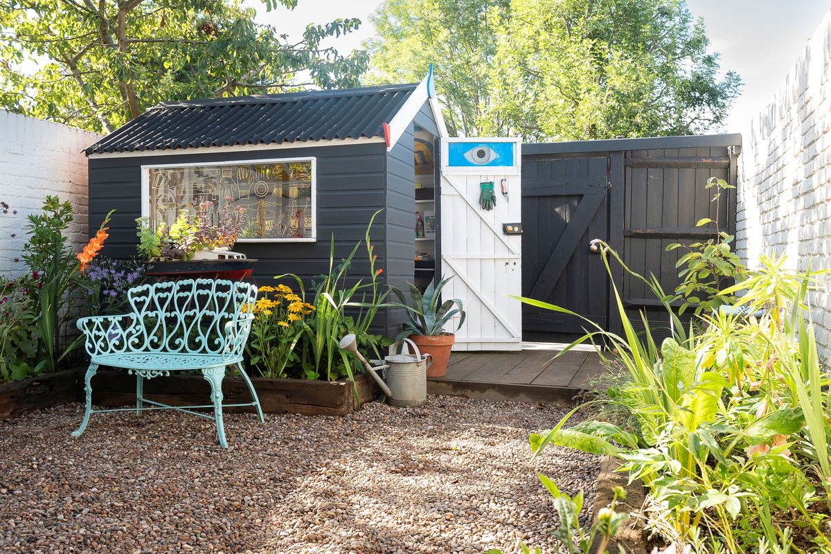 The black shed has an inner white door with an eye mural at the top of the door