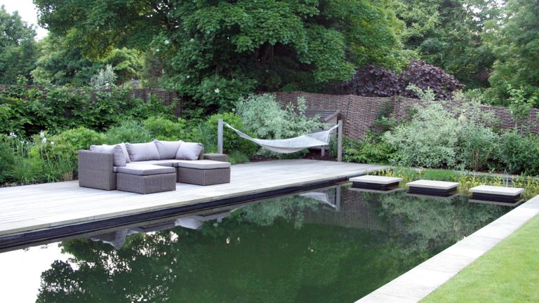 A pool deck area with natural swimming pool and hammock