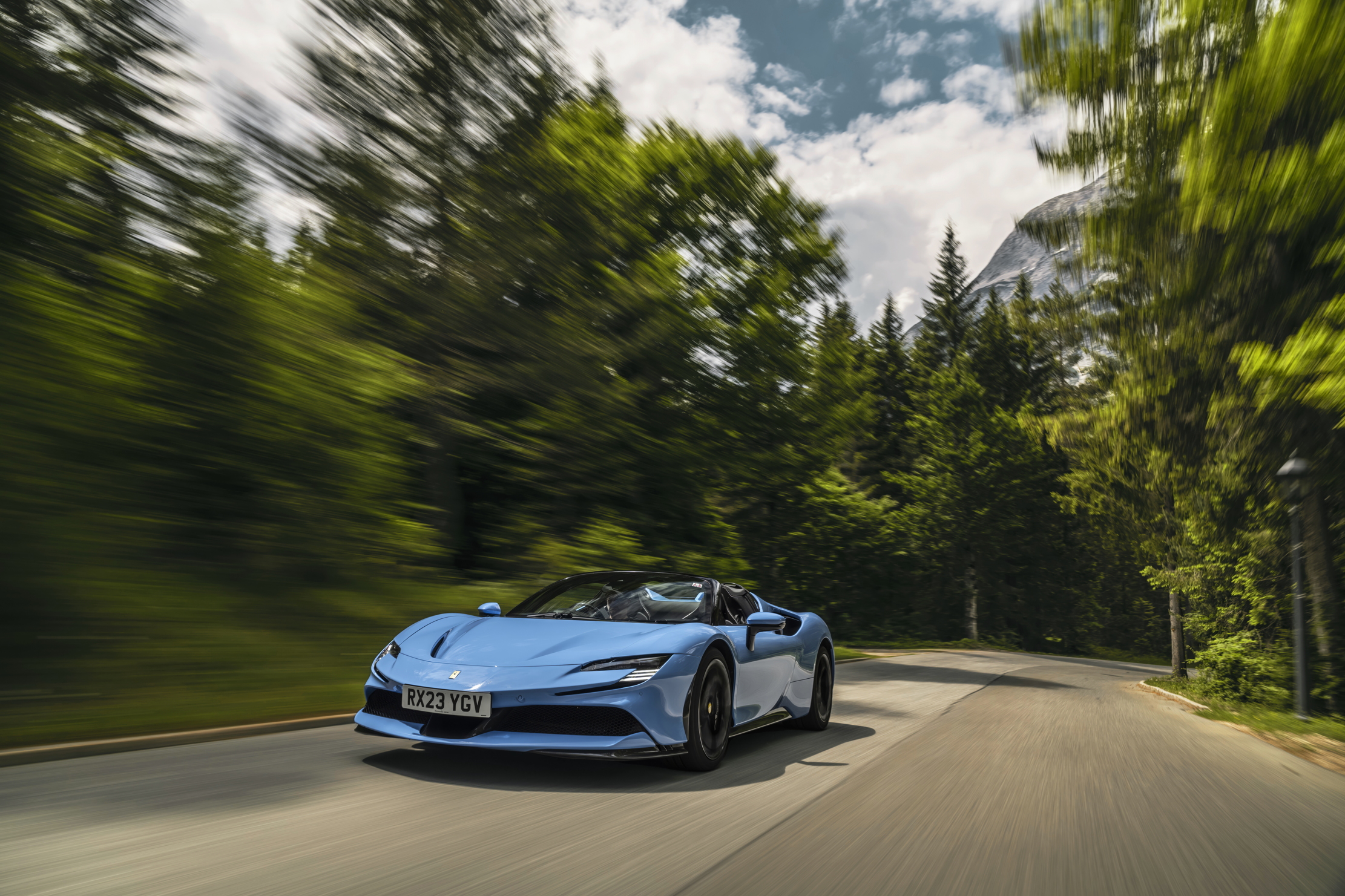 A Ferrari SF90 zooms through a forest on a road
