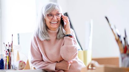 A woman with gray hair smiles as she talks on the phone.