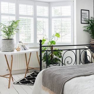 bedroom with white wall metal bed white windows and wooden floor