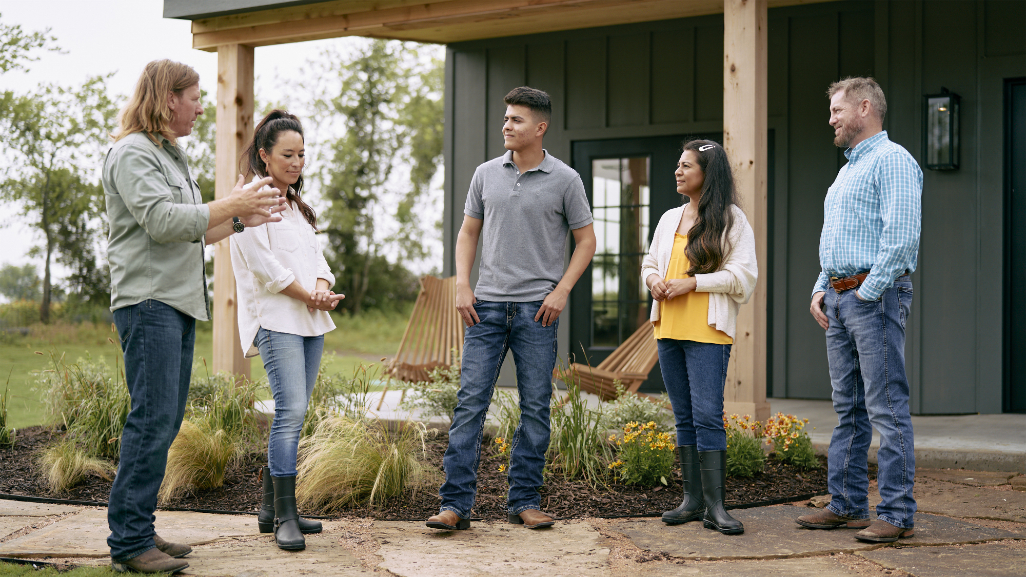 Chip Gaines, Joanna Gaines discuss plans with clients outside a house in Fixer Upper: Welcome Home