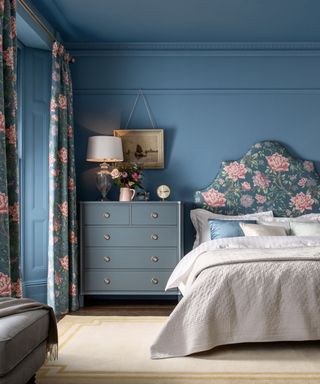 blue bedroom with large floral headboard and matching curtains