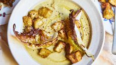 bowl of cauliflower soup with cauliflower leaves and croutons
