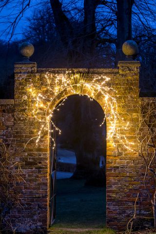 stone wall and archway lit up by fairy lights