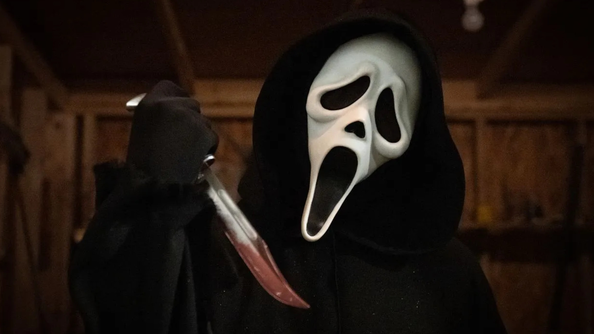 Ghostface trzymający nóż pokryty krwią podczas Krzyku 5.