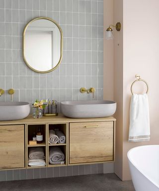 A natural wood floating vanity mounted to a tiled wall in a beige bathroom