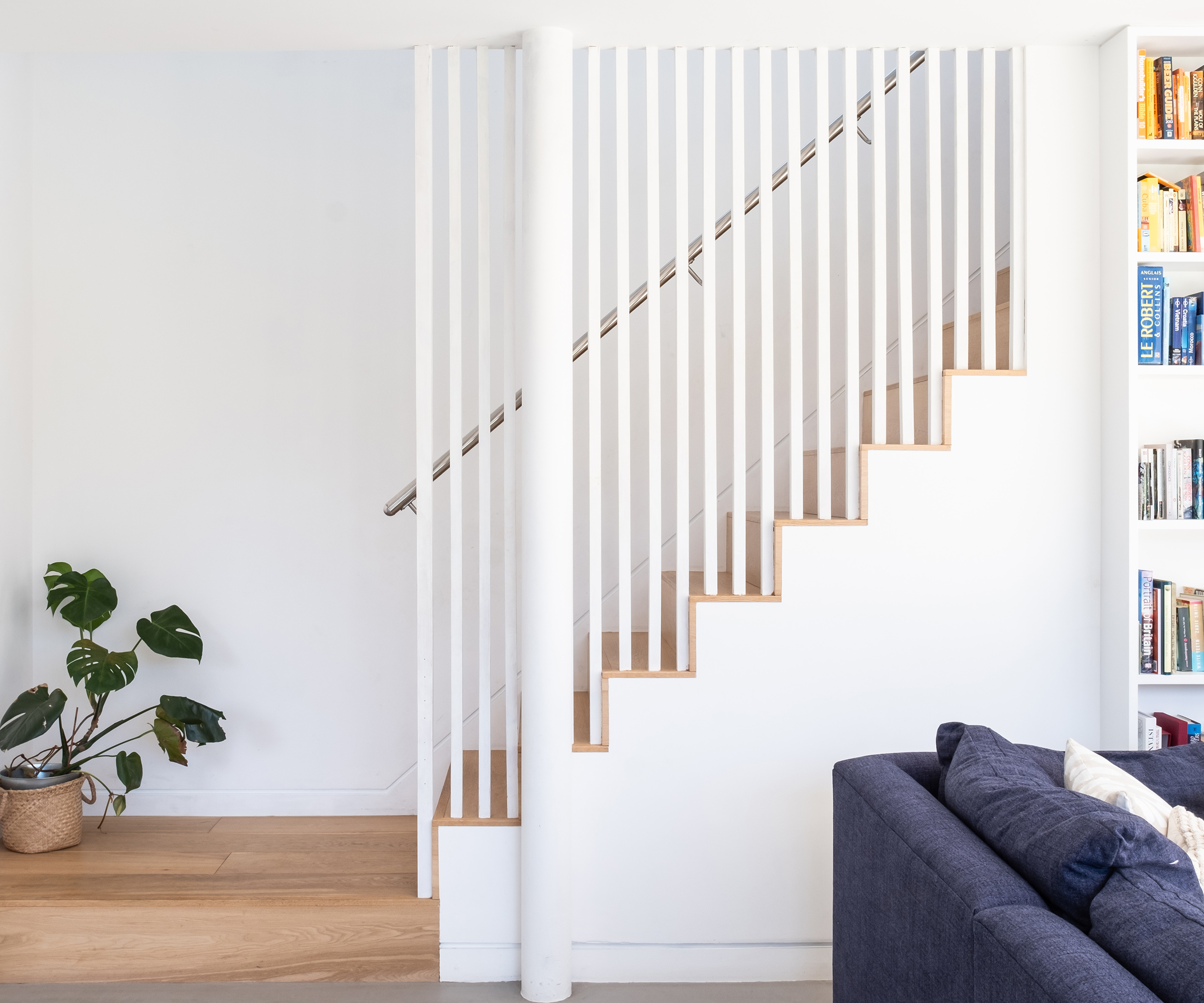A white staircase with long rails and wooden floor