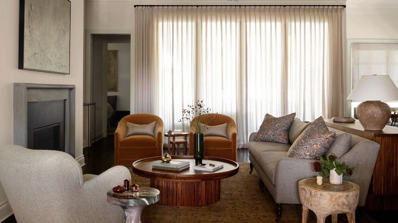 warm white living room with rust orange armchair , wooden coffee table and green rug