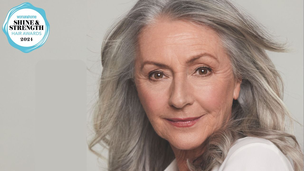 A close-in shot of a woman with bouncy grey hair with a logo of the 2024 woman&amp;home hair awards