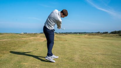 A golfer hitting an iron shot into the 13th at Royal Troon