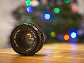 A close up of a Pnetacon F1.8 Lens in front of a Christmas tree