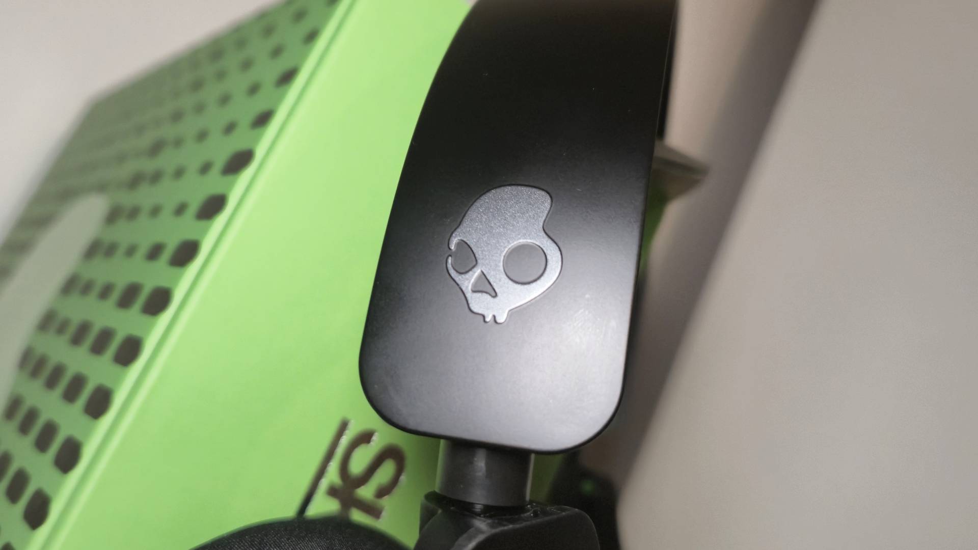 Close up of the Skullcandy logo on the side of a black gaming headset.
