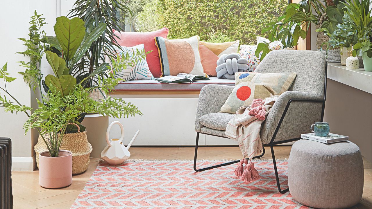 Seating area by picture window, with potted indoor plants and a patterned rug on the floor