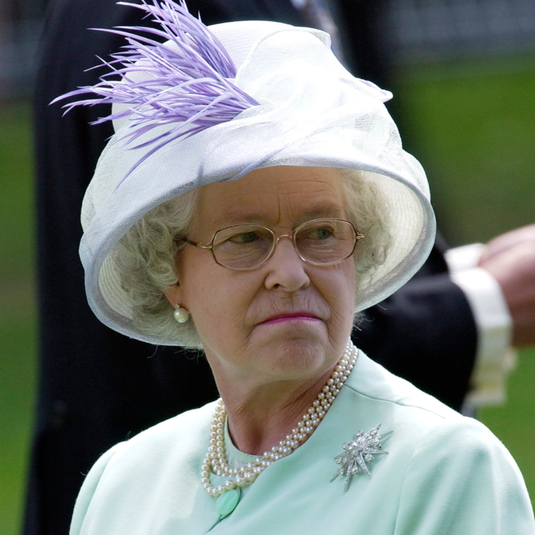 Queen Elizabeth wears a mint green suit and matching hat with a brooch and pearl necklace
