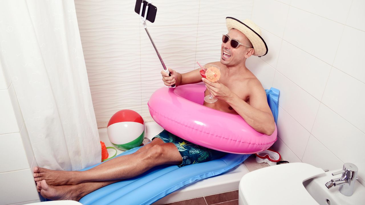 Man in an inner tube in the bathtub at home.